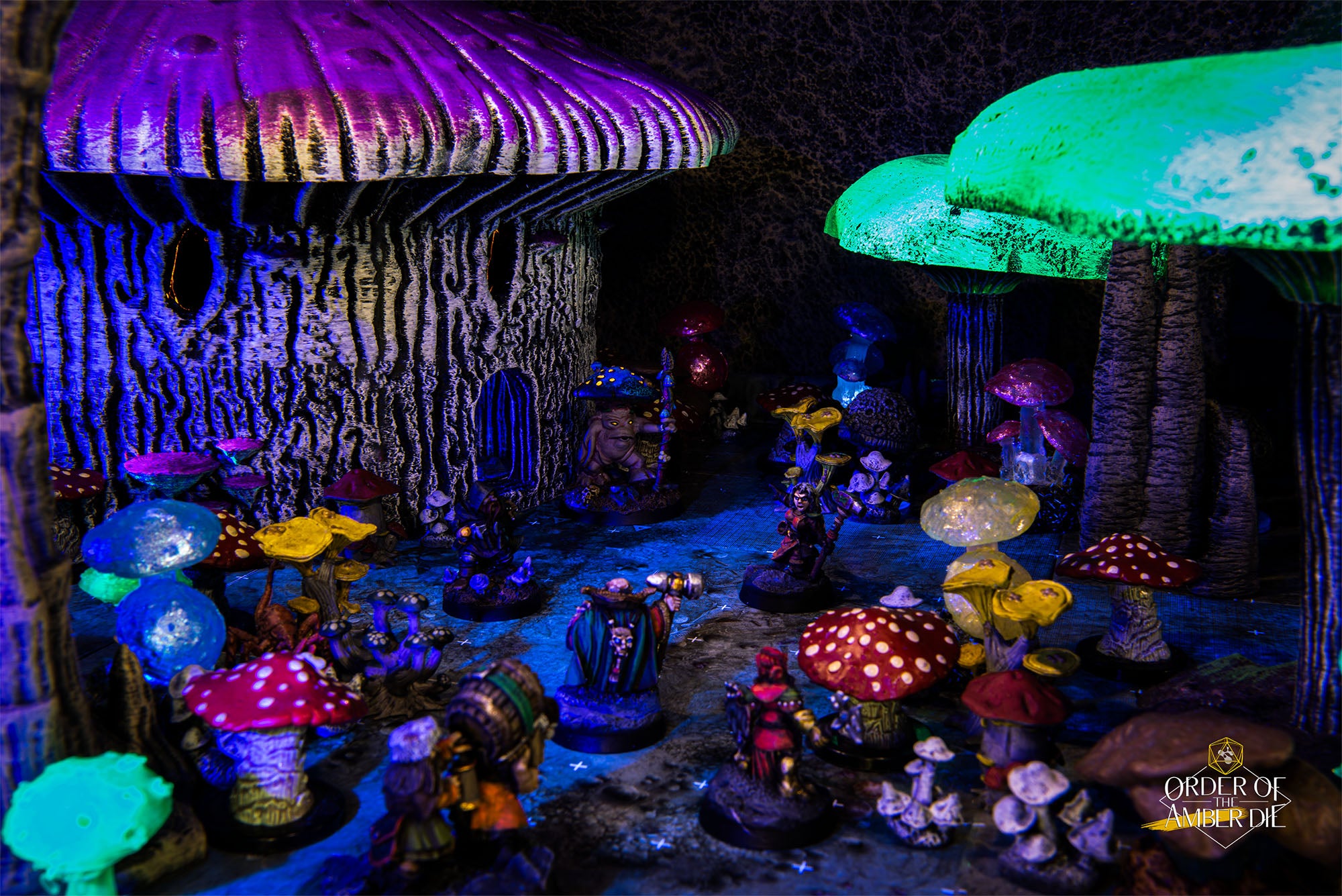 A tabletop miniature mushroom village lit up under a blacklight